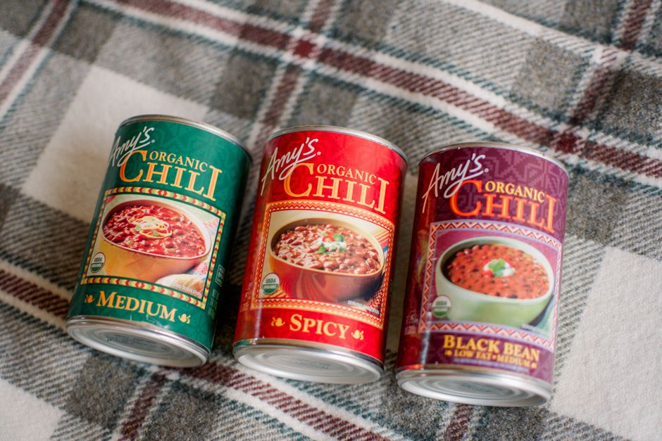 Three varieties of Amy's Organic Chili cans on a plaid picnic blanket.